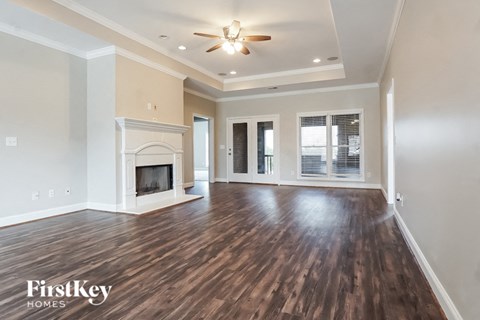 A spacious room with wooden floors and a fireplace.