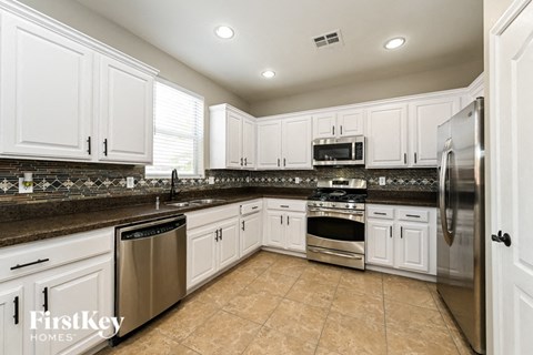 A kitchen with white cabinets and a tiled backsplash.