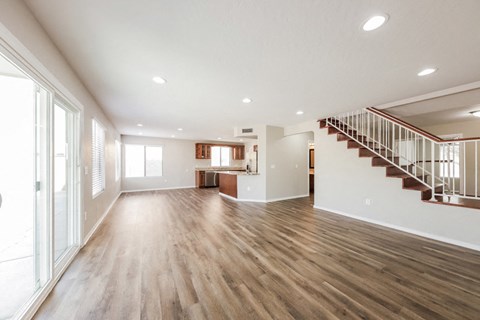 A spacious room with wooden floors and a staircase.