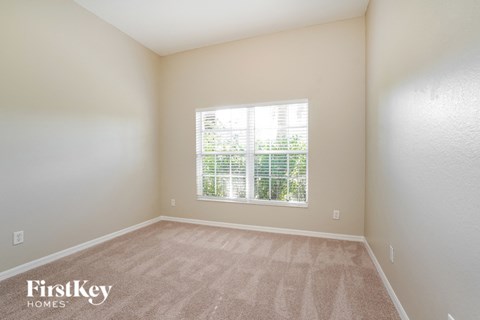 a spacious living room with a large window and beige carpet