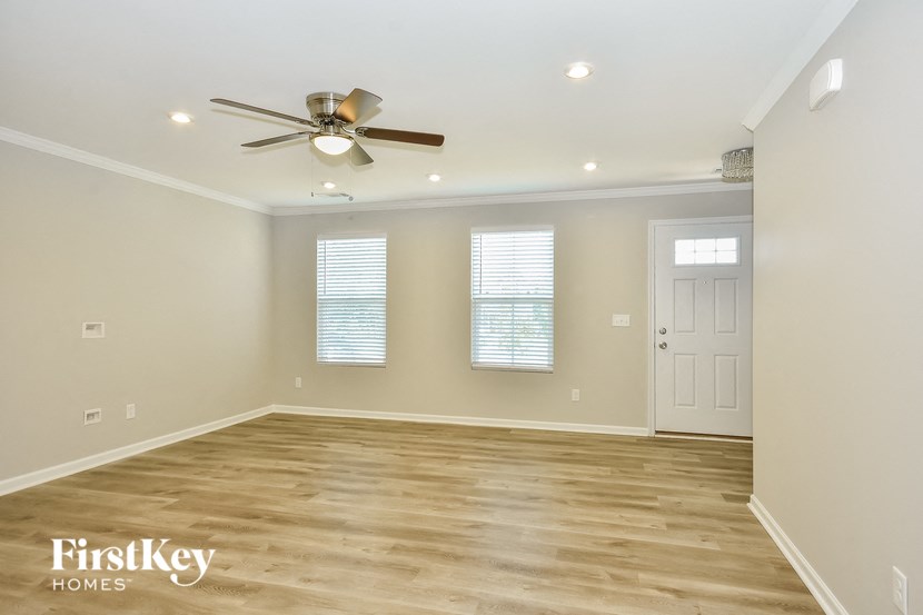 an empty living room with a ceiling fan and a door
