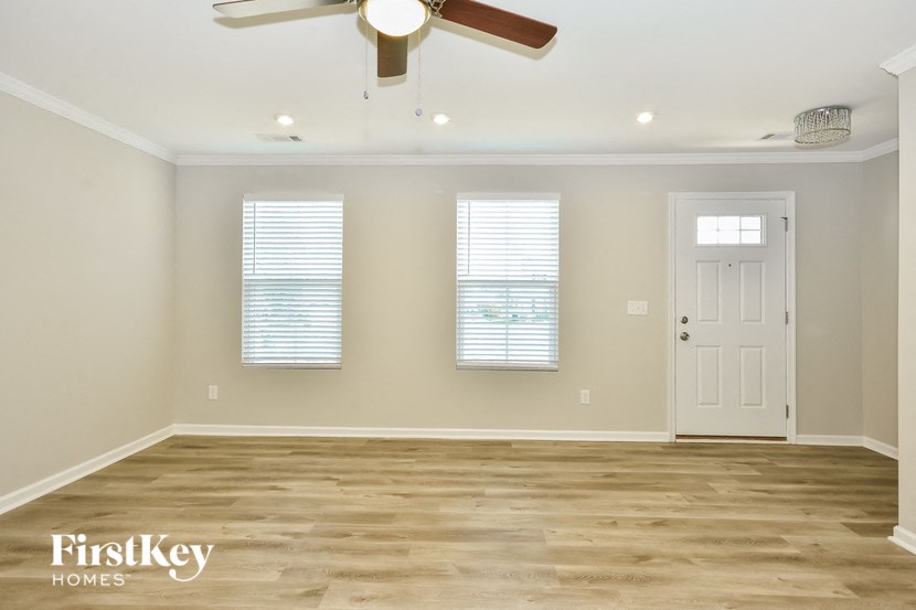 an empty room with a ceiling fan and two windows