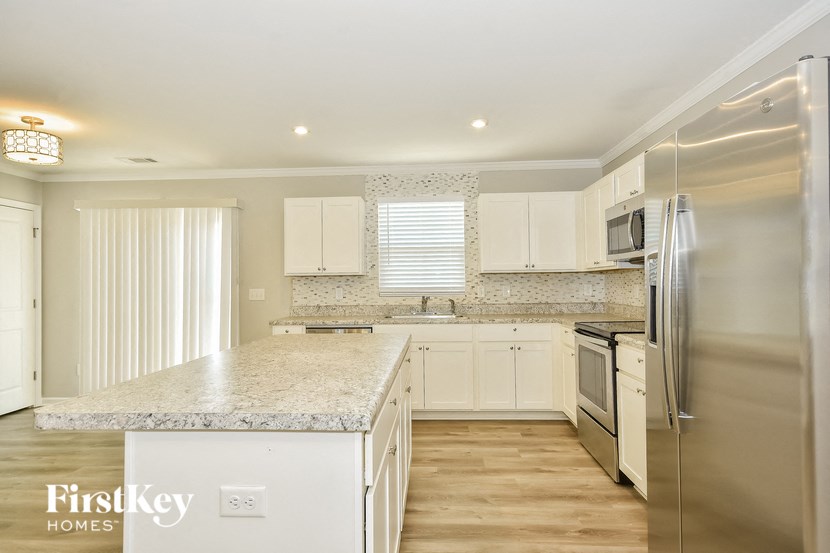 a kitchen with white cabinets and granite counter tops and stainless steel appliances