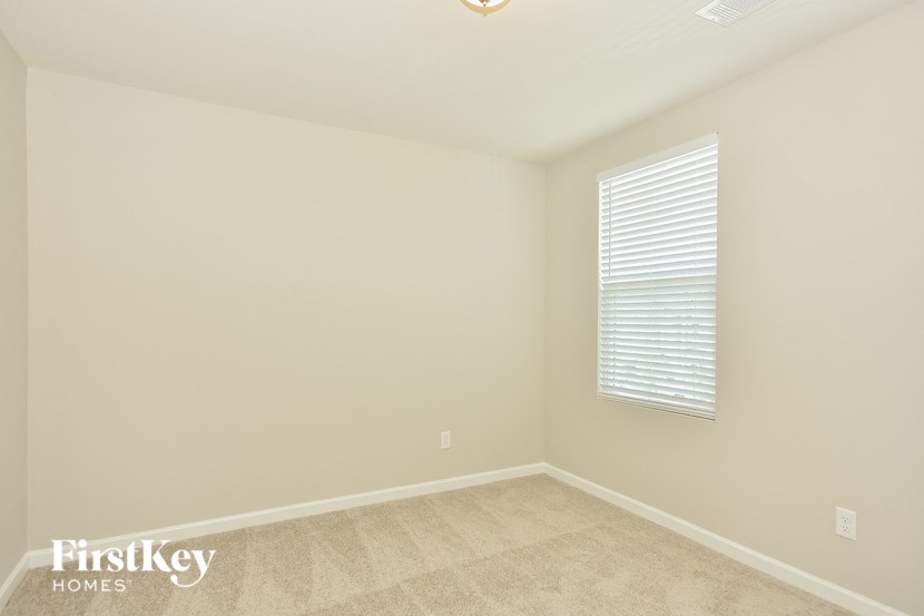 the upstairs bedroom has a large window and beige carpeting