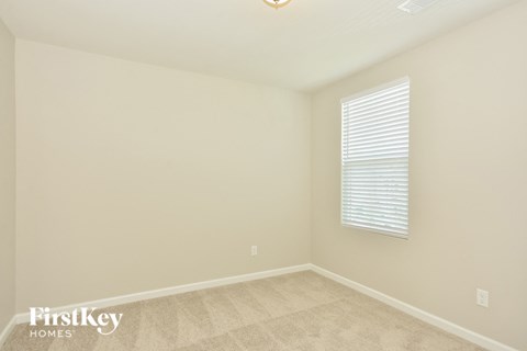 the upstairs bedroom has a large window and beige carpeting
