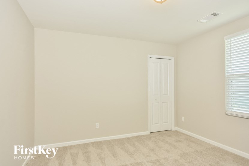 a bedroom with white walls and a white door and a carpeted floor