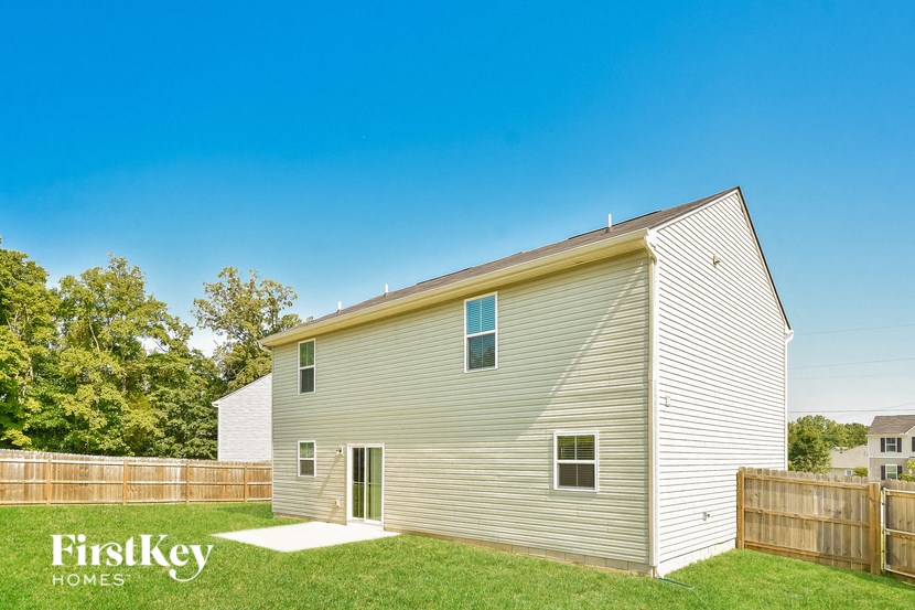 a backyard with a white house and a wooden fence