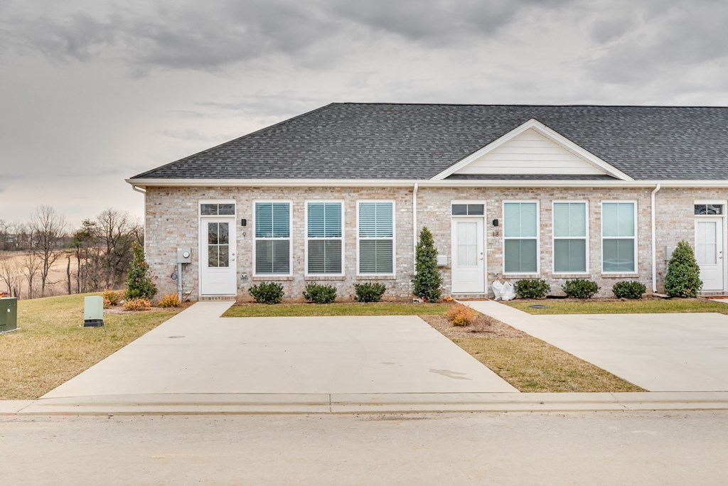 a brick house with blue shutters and a driveway
