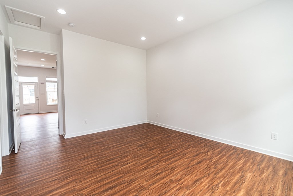 an empty living room with wood flooring and white walls
