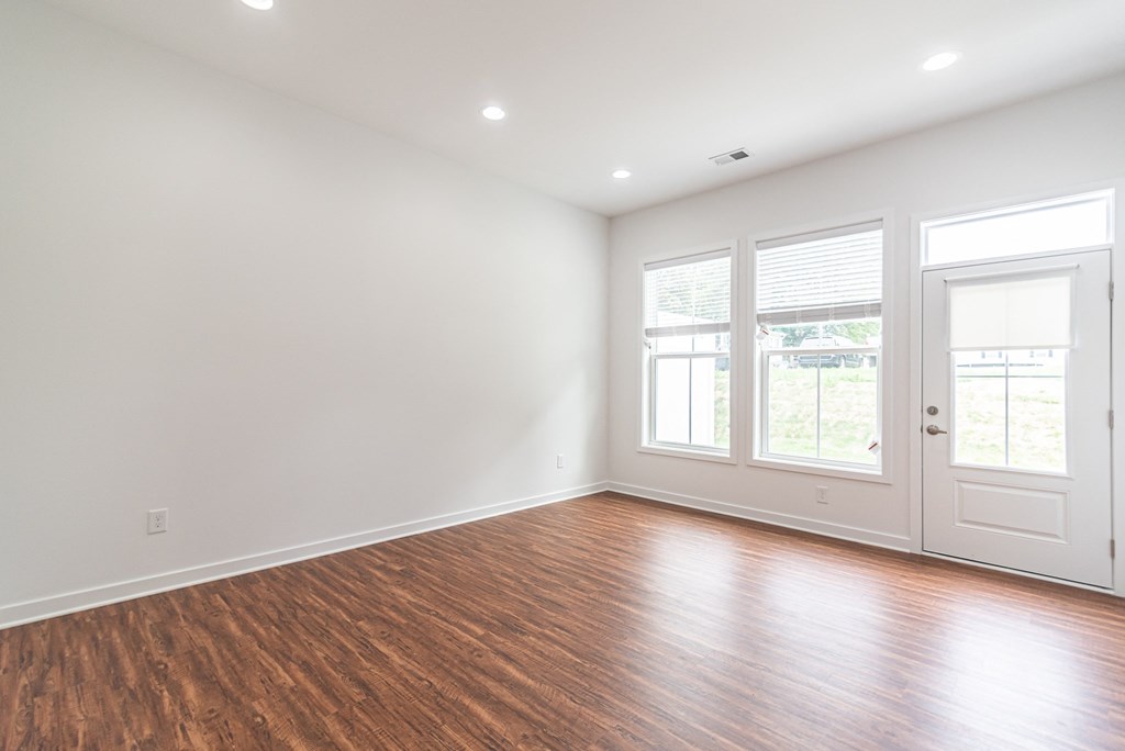 an empty living room with wood floors and white walls