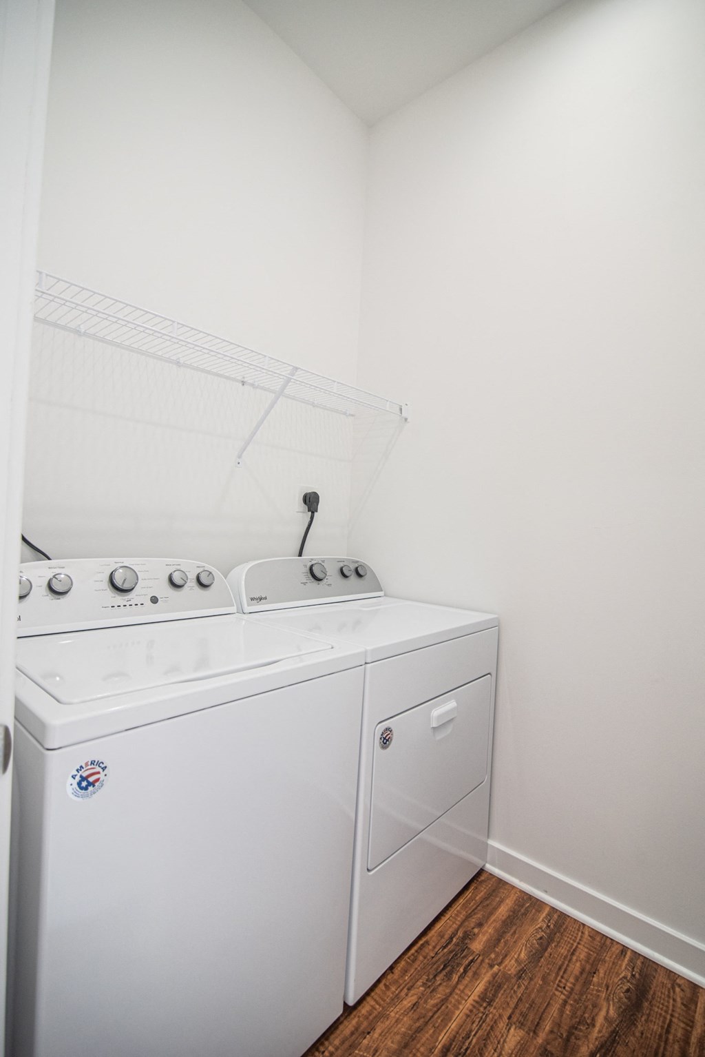 a washer and dryer in a room with a wooden floor and white walls