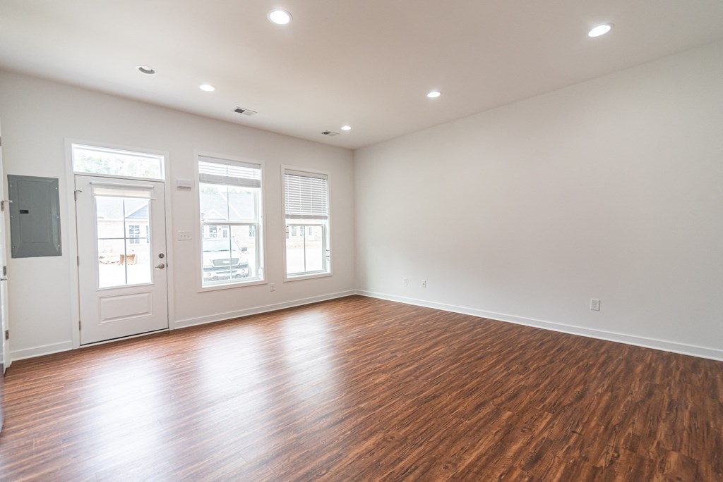 an empty living room with wood floors and white walls