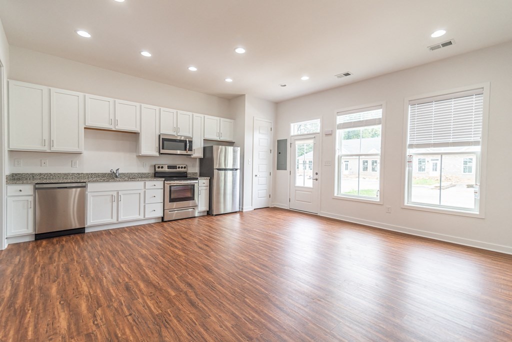 an empty kitchen with white cabinets and a wood floor