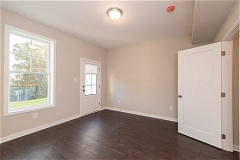an empty living room with a white door and a window