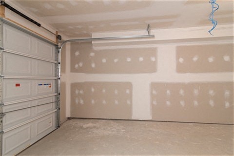 a garage with a bunch of white cabinets and a wall
