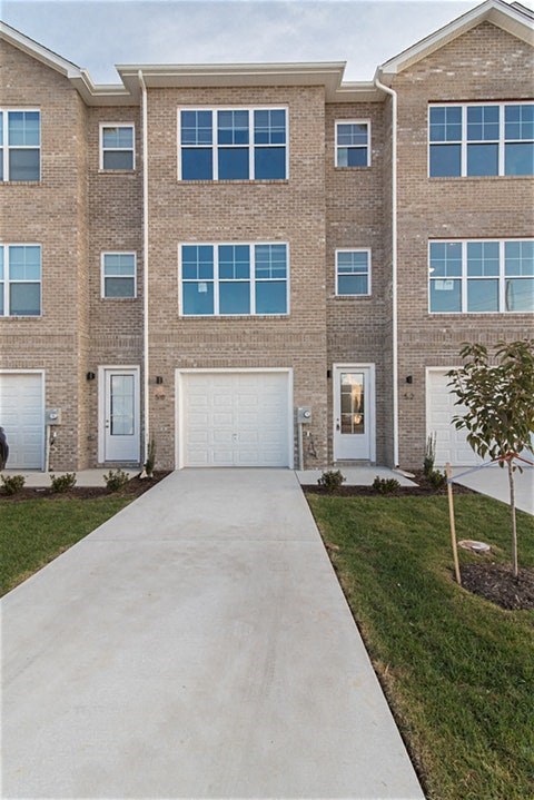 a sidewalk in front of a brick building with a white garage door