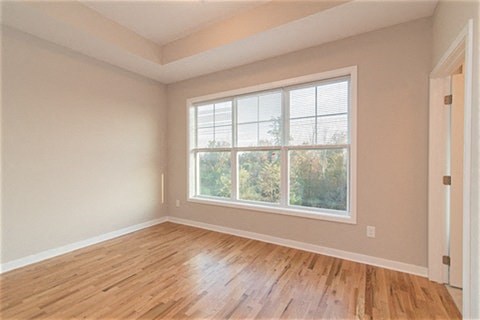an empty living room with a large window and wooden floors