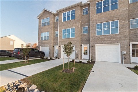 a sidewalk in front of a brick house with a white garage door