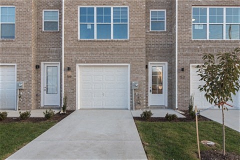 a sidewalk in front of a brick building with a white garage door