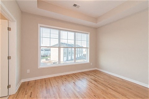 an empty living room with a large window and wooden floors