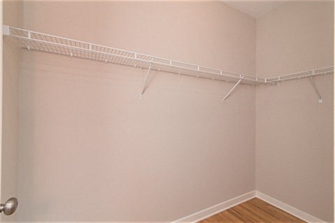 a empty closet with a white wall and a wire rack on the wall