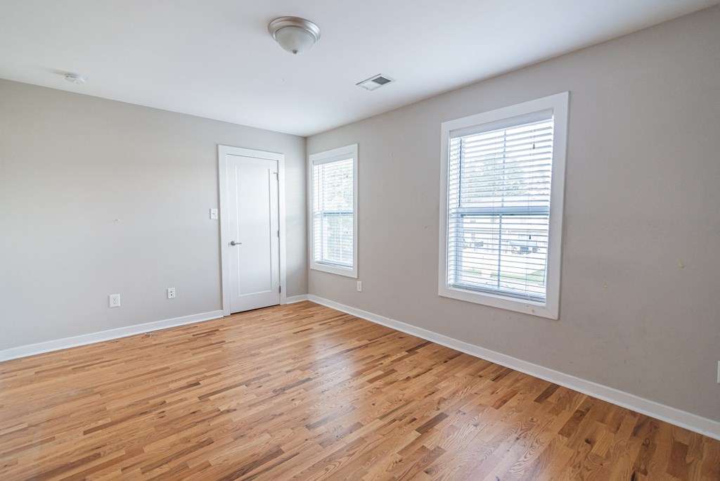an empty living room with wood floors and a window