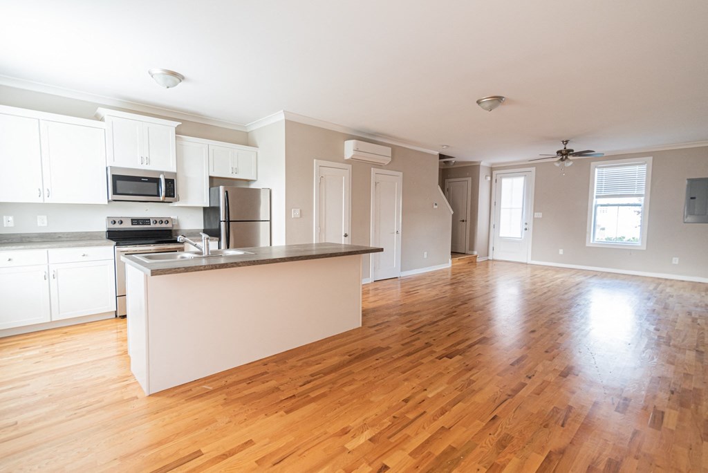 an empty kitchen and living room with a hard wood floor