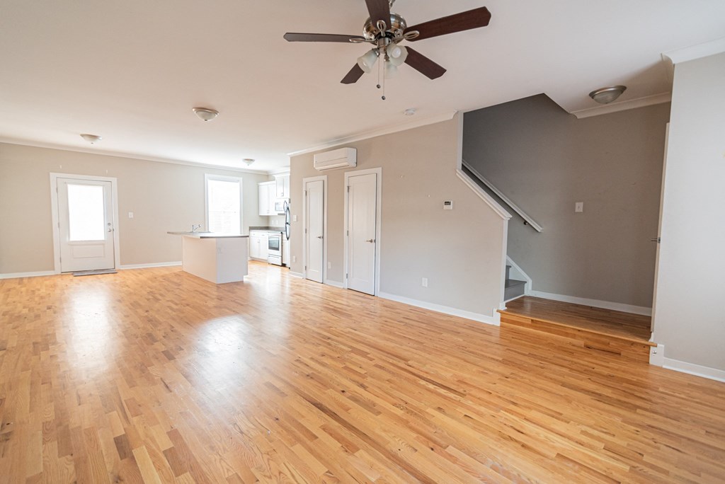 an empty living room with wood floors and a ceiling fan