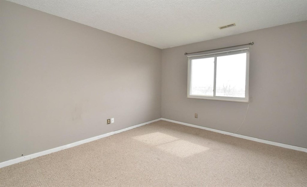 an empty living room with a window and carpet