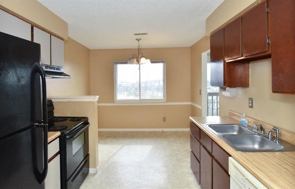 an empty kitchen with black appliances and wooden cabinets