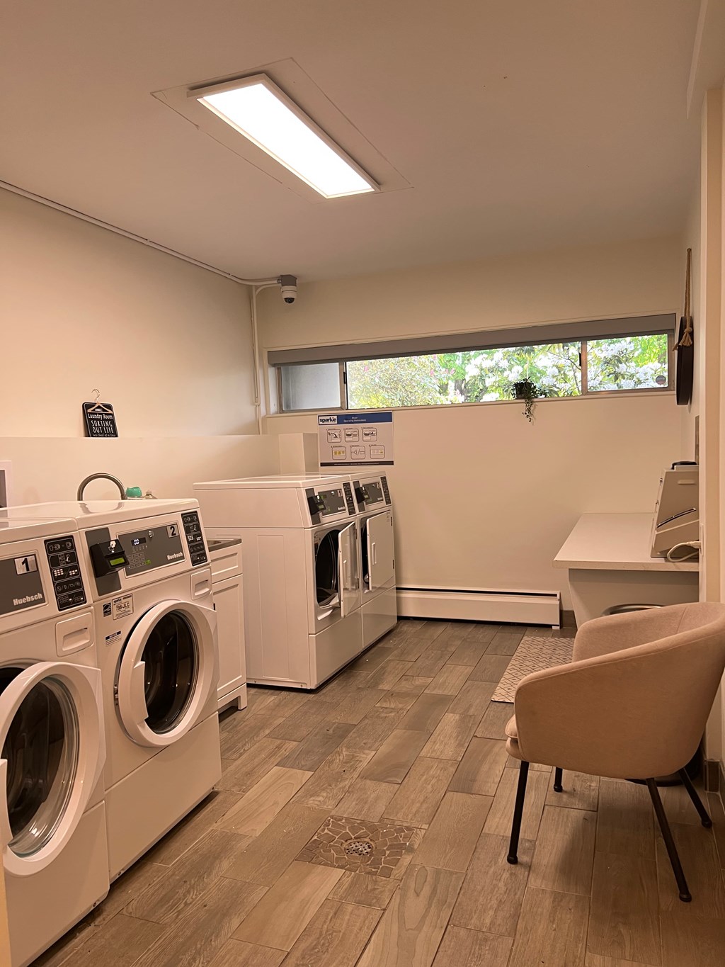 A laundry room with washing machines and a chair.