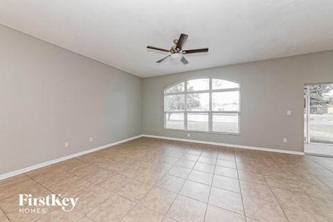 A spacious room with a ceiling fan and large windows.