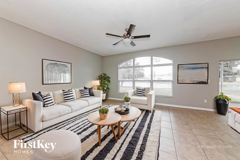 A living room with a white couch, a wooden coffee table, and a ceiling fan.