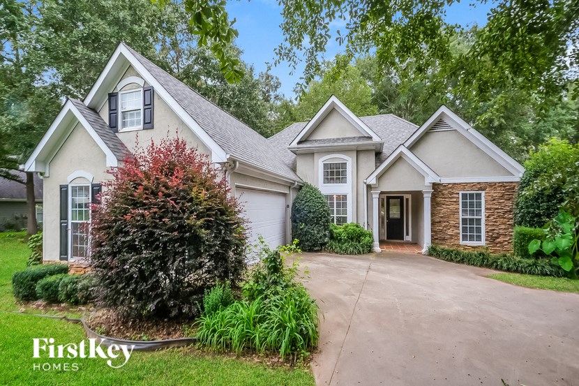 a home with a driveway and a white house