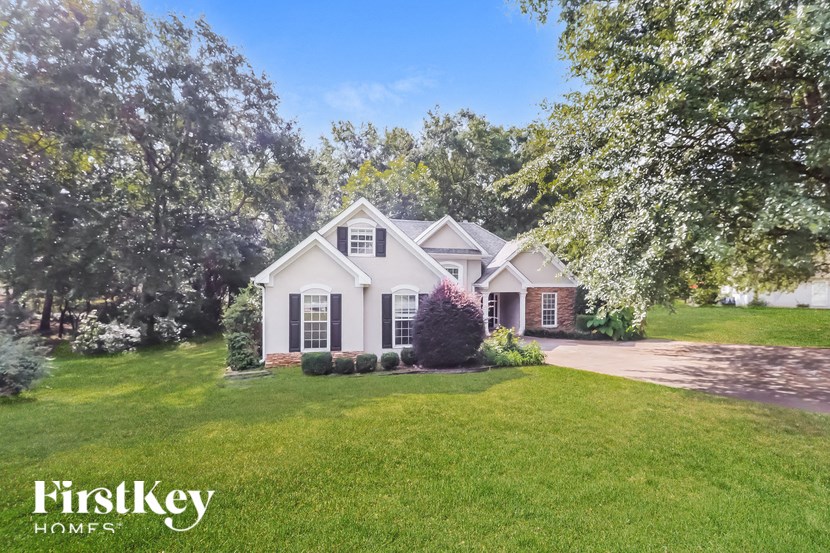 a white house with a lawn and trees