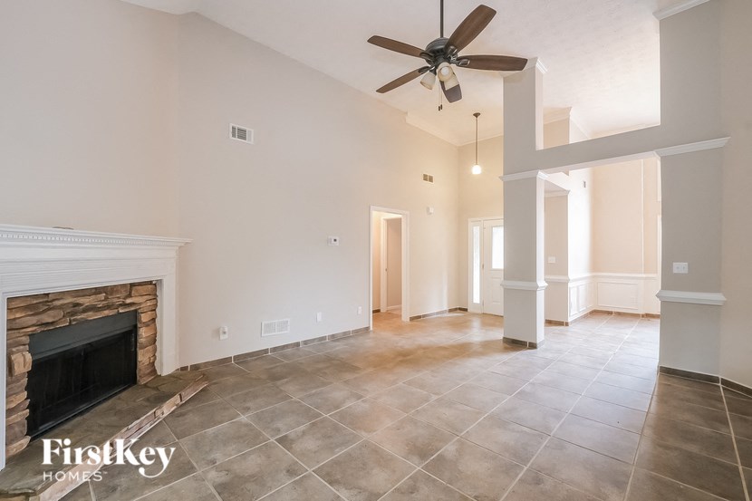 a living room with a fireplace and tiled floors and a ceiling fan