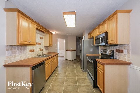 full kitchen with stainless steel appliances and wooden cabinets and tile floors