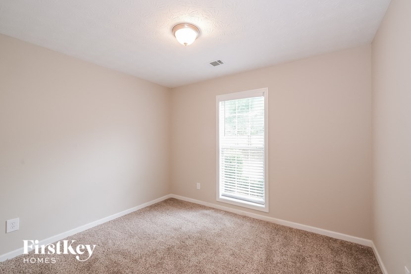 a bedroom with beige carpet and a window