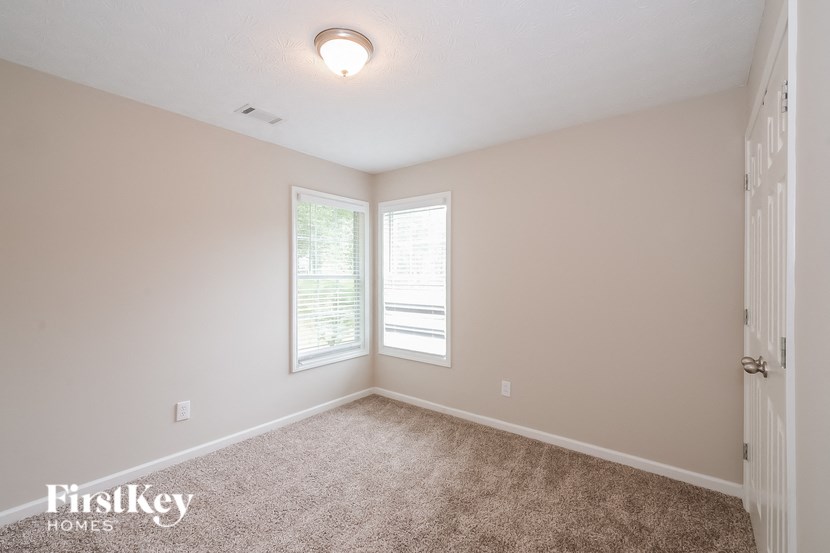 a bedroom with a carpeted floor and two windows