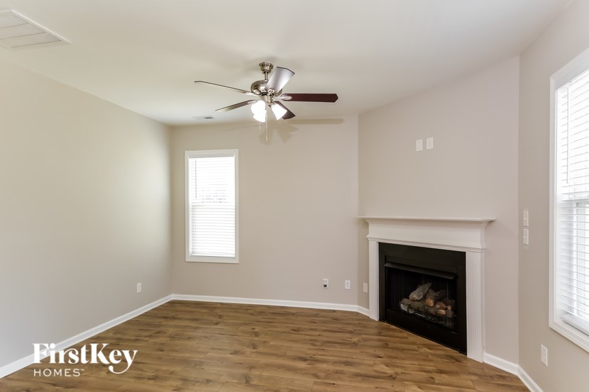 A spacious living room with a fireplace and a ceiling fan.