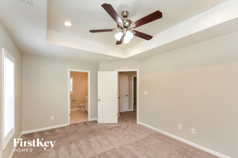 A spacious room with a ceiling fan and two doors leading to other rooms.