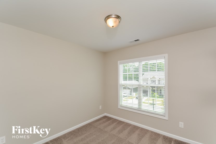 A room with a window covered in blinds and a light on the ceiling.