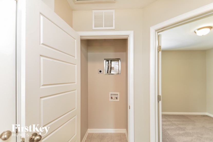A white door with a gold handle is open to a hallway.