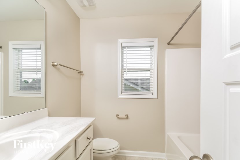 A white bathroom with a toilet, sink, and window.