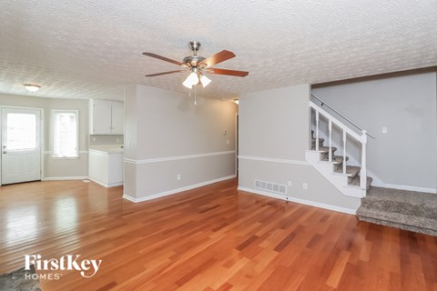 A spacious room with wooden floors and a staircase.