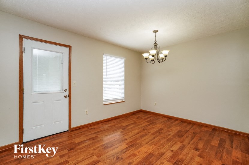 the living room of an empty house with wood flooring and a white door
