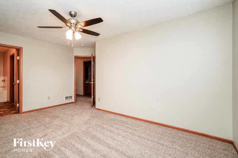 a living room with a white wall and a ceiling fan