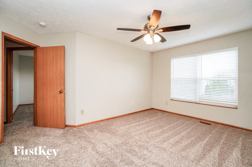 an empty living room with a ceiling fan and a window