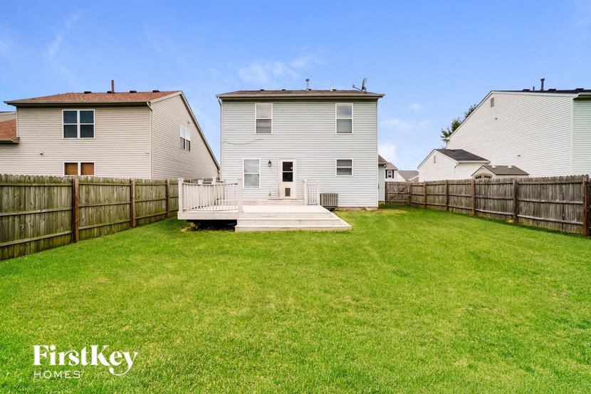 a backyard with a deck and a white house