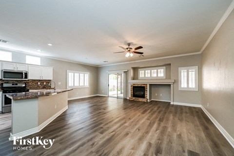 A spacious living room with a fireplace and a kitchen area with a countertop and appliances.